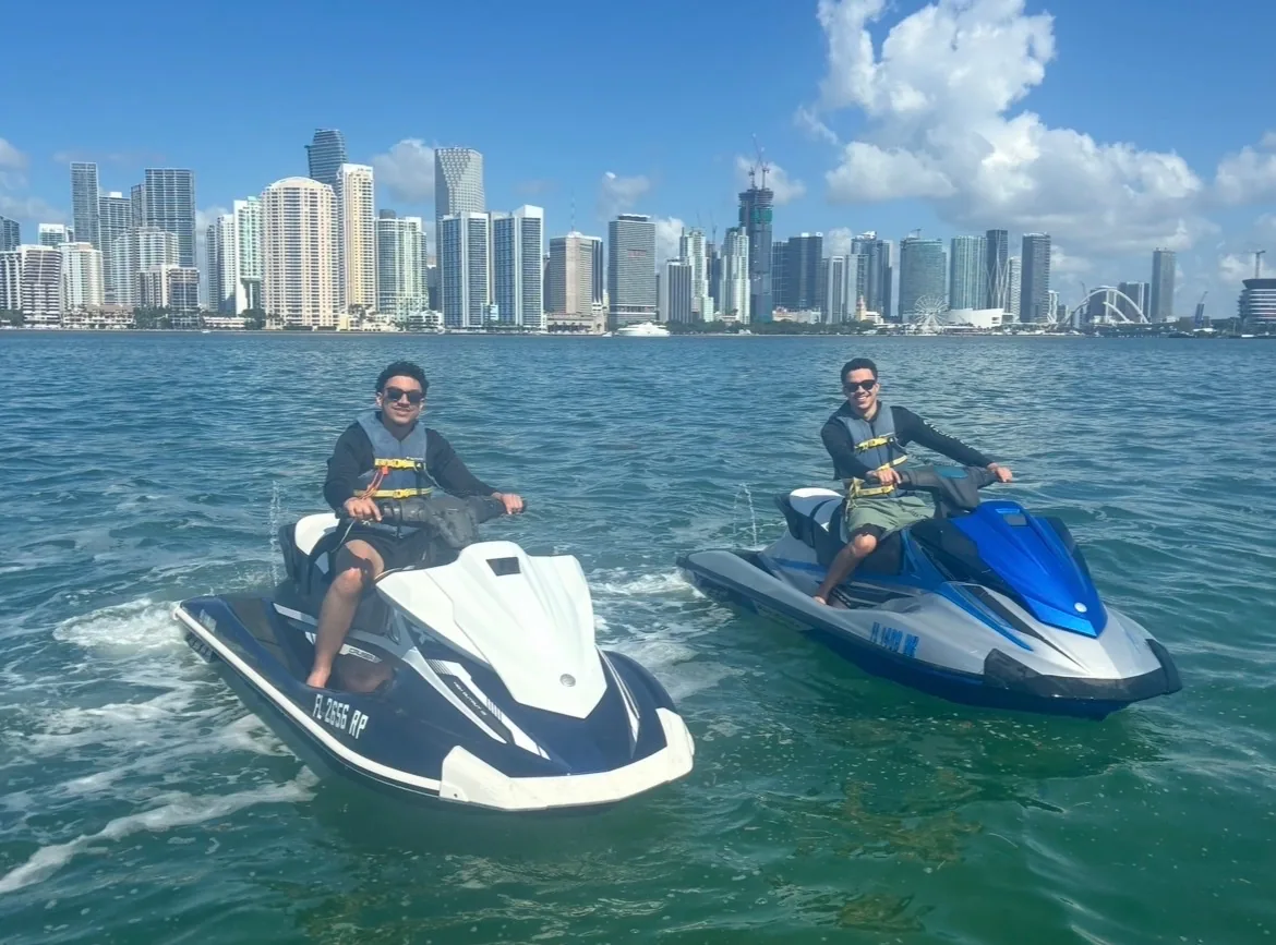 Two riders on Yamaha WaveRunners with the full Miami skyline behind them